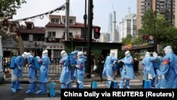 Работници во заштитни одела се подготвуваат да дезинфицираат станбен комплекс во областа Хуангпу, по избувнувањето на коронавирус во Шангај, Кина на 20 април 2022 година.