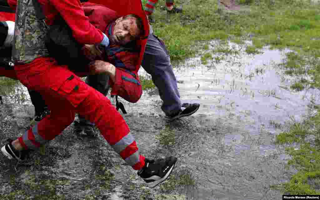 Lucrători medicali cară un bărbat rănit în urma bombardamentelor din Harkov pe 27 aprilie.