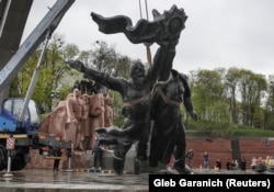 A Soviet-era monument to friendship between Ukraine and Russia is lowered to the ground by a crane after being cut from its plinth in central Kyiv on April 26.