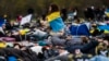 Magukat jórészt halottnak tettető tüntetők tiltakoznak az orosz energiahordozók importja ellen a berlini Bundestag előtt 2022. április 6-án, nem sokkal a bucsai mészárlás kiderülte után