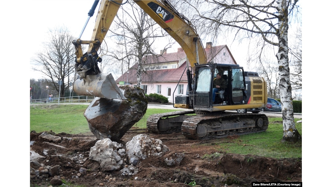 Un excavator scoate din pământ o piatră memorială de fabricație sovietică, din parohia Madliena/Letonia, la aproximativ 60 de kilometri est de Riga, pe 26 aprilie.