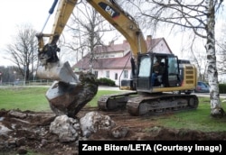 An excavator pulls a Soviet-made memorial stone out of the ground in Latvia’s Madliena Parish, around 60 kilometers east of Riga, on April 26.