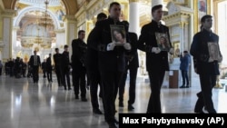 Men carry portraits of (from right) Valeria Hlodan and her mother, Lyudmyla Yavkina, who were killed in their apartment by Russian shelling along with 3-month-old infant Kira Hlodan during a funeral ceremony in Odesa on April 27, 2022.