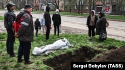 The funeral of a Mariupol resident killed during the Russian occupation is held beside a street on April 19.