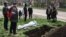 The funeral of a Mariupol resident killed during the Russian occupation is held beside a street on April 19.