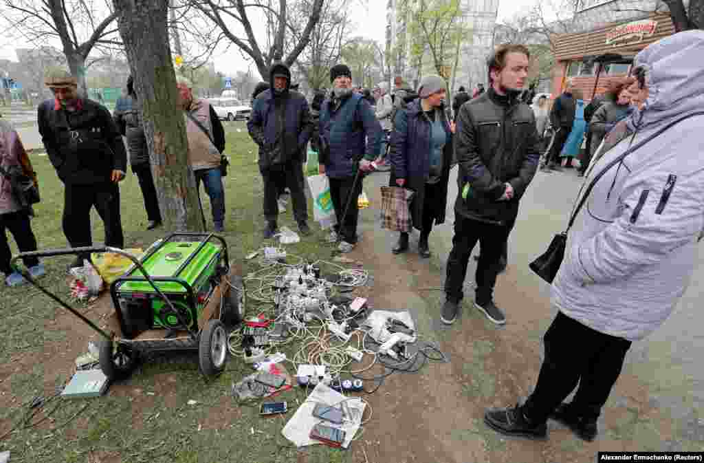 Local residents of Mariupol wait for their phones and electronic devices to be charged from a portable generator on April 19.&nbsp;