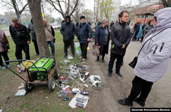 Stanovnici Mariupolja čekaju da se njihovi uređaji napune strujom iz prenosnog agregata na pijaci u tom lučkom gradu, 19. april 2022.