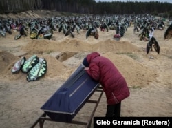 Женщина плачет над гробом родственника, погибшего во время обстрела города Ирпень российскими войсками. 17 апреля 2022 года.