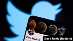 Llogaria në Twitter e Elon Muskut shihet në një telefon të mençur para logos së Twitter-it në këtë ilustrim fotografik të marrë më 15 prill 2022.