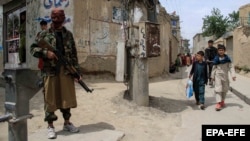 A Taliban member stands guard in an area surrounding a Kabul school after bomb blasts on April 19. At least six people were killed.