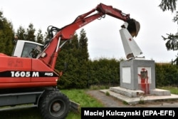 An excavator topples the obelisk of a memorial to the Red Army in the village of Garncarsko, Poland, on April 20.