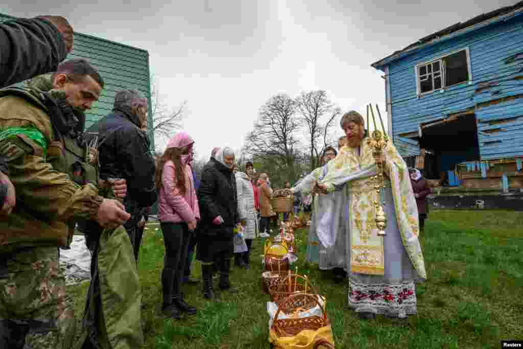 An Orthodox priest sprinkles holy water on believers during the Orthodox Easter service next to the Nativity of the Holy Virgin Church in Peremoha.