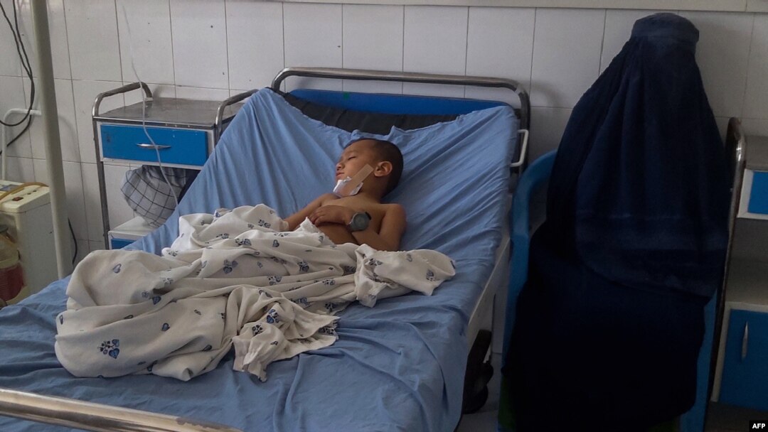 A burqa-clad Afghan woman sits next to a child receiving treatment at a hospital after he was injured in a bomb blast in Kunduz on April 21.
