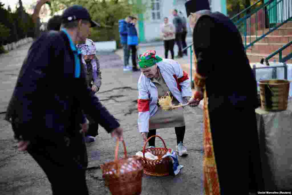 Свештеник ги благословува традиционалните корпи со велигденска храна за време на велигденската маса во украинската православна катедрала на Светата Троица во јужниот град Запорижје.