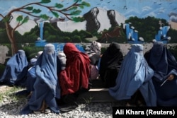 Afghan women wait to receive a food package being distributed by a Saudi humanitarian aid group at a distribution center in Kabul in April.