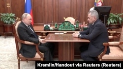 Vladimir Putin și ministrul apărării, Serghei Șoigu, la Moscova, 21 aprilie 2022. Pe tot parcursul întâlnirii de câteva minute, liderul rus a stat rezemat pe scaun și a strâns colțul mesei cu mâna dreaptă, ridicând semne de întrebare cu privire la starea sa de sănătate.