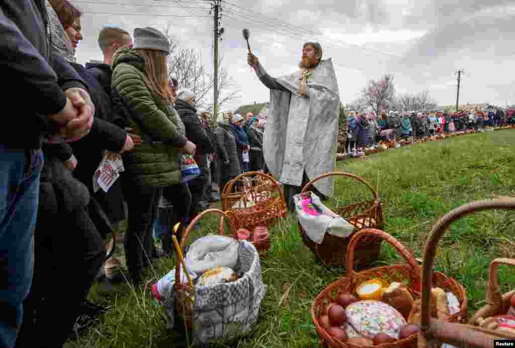 Slujba de Paște în apropierea ruinelor bisericii din satul Hostroluchia, din vecinătatea Kievului, Ucraina, 24 aprilie 2022.