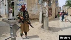 A Taliban fighter stands guard at the site of an explosion in Kabul last month.