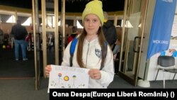 Olia, 11 ani, poartă un afiș în care scrie ”Paște Fericit împreună! Noi credem în victorie!