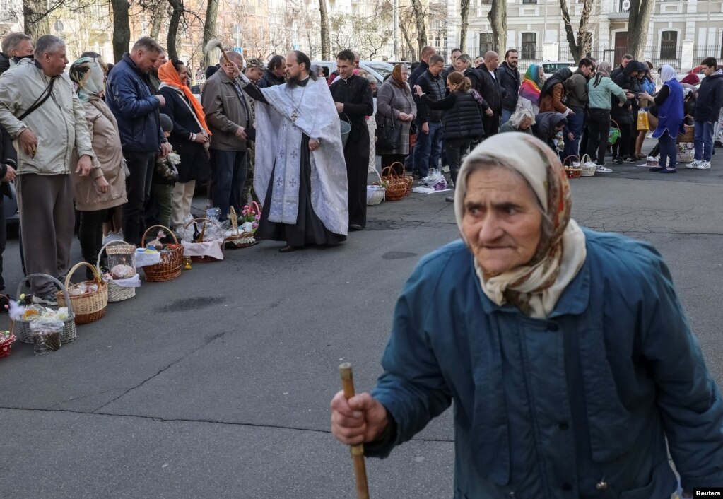 Një prift ortodoks spërkat me ujë të shenjtë besimtarët gjatë shërbimeve për Pashkët Ortodokse jashtë Katedrales Volodymysky në Kiev.