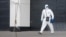 A medical specialist wearing protective gear walks outside a hospital for patients infected with the coronavirus on the outskirts of Moscow on March 23.