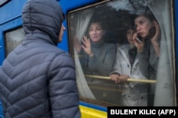 Family members on an evacuation train say goodbye to a young man staying behind at the central train station in Odesa on March 6. The state railway is transporting about 60,000 Ukrainians per day from the south, north, and east of the country to destinations in the west.