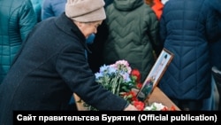 A woman in Buryatia pays her respects to a Russian serviceman who died in the invasion of Ukraine. 