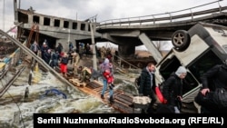 Oamenii din Irpin traversează un pod distrus, după zile de bombardamente intense asupra singurei rute de scăpare din zonă, în timp ce trupele rusești avansează spre Kiev, 7 martie 2022. 