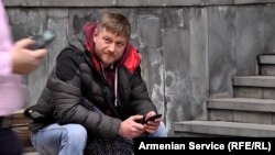 . A Russian man reading news on his mobile in the center of Yerevan.