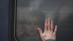 Një fëmijë përshëndetet me babanë e tij derisa treni niset nga stacioni në Kiev.