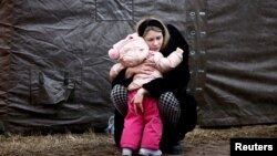 Украинка прегръща дете във временен бежански лагер край град Пшемишъл, Полша, 28 февруари 2022. По данни на ООН бежанците от страната са повече от 1,7 млн., предимно жени и деца.