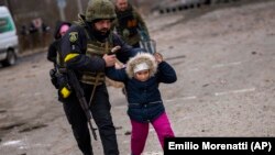 Një oficer policie ukrainas bashkë me një fëmijë në Irpin, në periferi të Kievit, Ukrainë, më 7 mars 2022.
