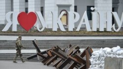 Ukrajinski vojnik prolazi pored natpisa "Volim Ukrajinu" i protutenkovske barikade u centru Kijeva, 7. mart 2022.