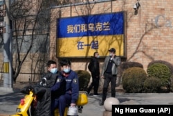 A sign outside the Canadian Embassy showing the Ukraine flag reads "We stand together with Ukraine" in Beijing on March 3. The sign was later defaced with graffiti decrying NATO.