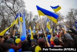 Участники антивоенного митинга в поддержку Украины держат украинские флаги. Алматы, 6 марта 2022 года