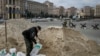 A man fills sandbags in the center of Kyiv on March 7 as volunteers from the Territorial Defense Forces patrol in the background.