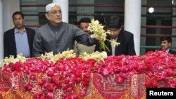 ولسمشر آصف علي زدراري په ګړي خدابخش کې د بې نظیر بوټو پر مزار د ګلونو څادر غوړوي.۲۷ م ډسمبر ۲۰۱۱م کال
