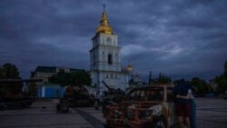 Doi tineri se îmbrățișează în timp ce privesc tancurile rusești distruse, instalate ca simbol al războiului, în fața catedralei Sfântul Mihail din Kiev, Ucraina, 23 iunie 2022.