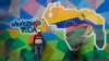 Muškarac prodaje telefonske kablove ispred murala karte Venezuele koja uključuje gvajansku teritoriju Esekibo. Karakas, Venecuela, 11. decembar 2023.
