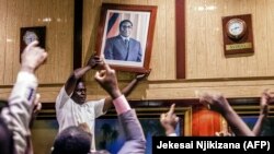 Портрет Мугабе снимают со стены после отставки президента. 21 ноября 2017 года.