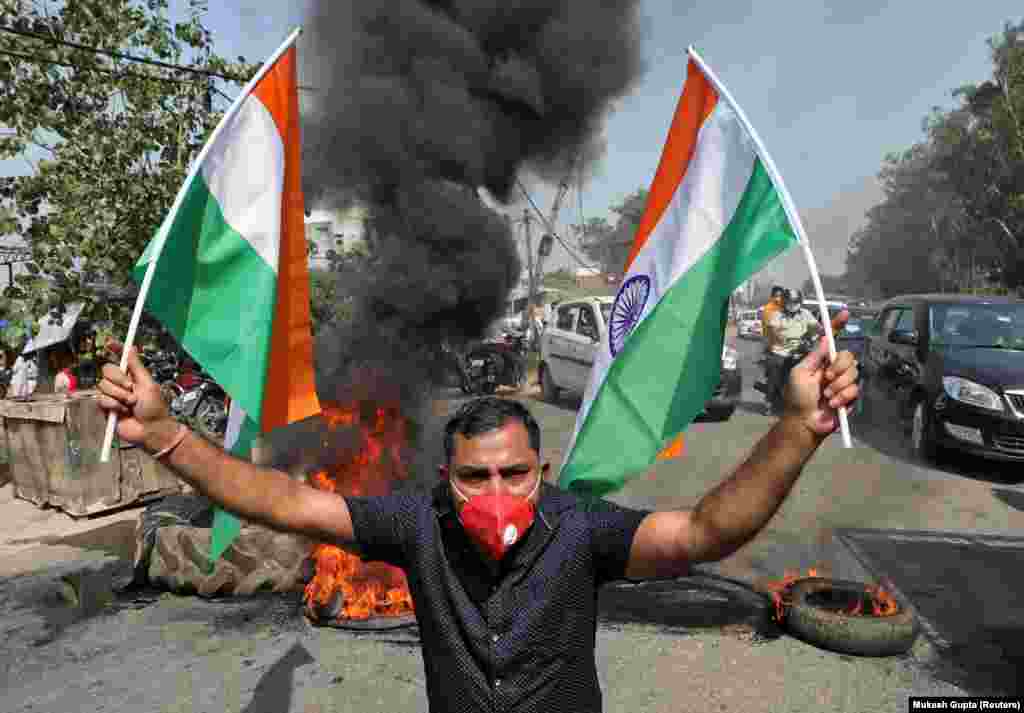 A demonstrator holds Indian national flags in front of burning tyres during a protest against China, in Jammu, June 17, 2020. Several demonstrations took place across India in reaction to the conflict with China.