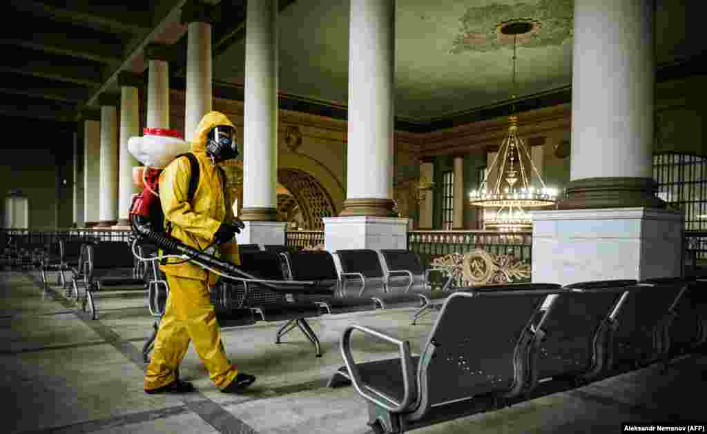 A serviceman of Russia&#39;s Emergencies Ministry, wearing protective gear, disinfects the Kievsky railway terminal amid the COVID-19 pandemic in Moscow.