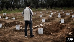 په يونان کې يو کس د هغو کډوالو له قبرونو سره ولاړ دی چې له ترکيې څخه د وراوښتو پر مهال مړه شوي دي ـ انځور له ارشيفه