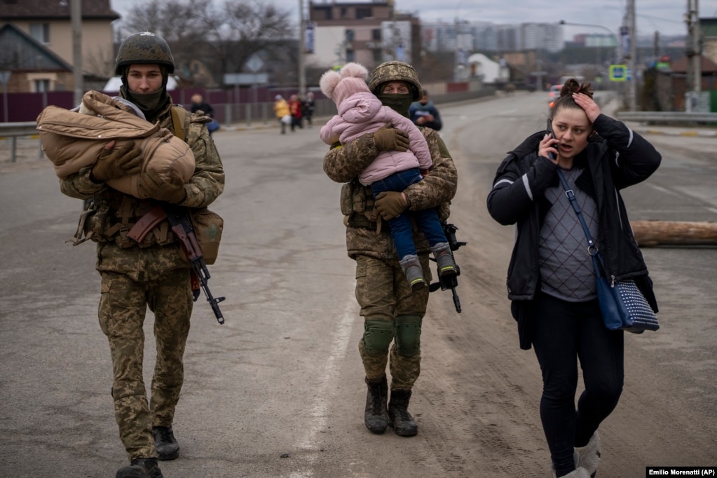 Ushtarët ukrainas duke bartur foshnja, teksa i ndihmonin një familjeje në ikje për të gjetur një automjet, pas kalimit të lumit të Irpinit, në periferi të Kievit, më 5 mars.