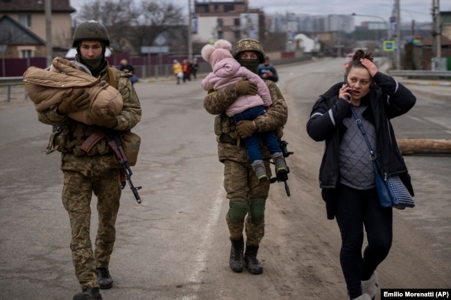 Украинские военные несут детей, помогая эвакуироваться бегущей от войны семье. Окраина Киева, 5 марта 2022 года