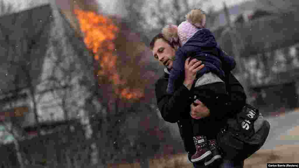 Egy férfi menekül, karjában gyermekével Irpinyből 2022. március 6-án. Az orosz csapatok ekkor éppen előrenyomultak Kijev felé