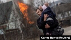 Мужчина с ребенком после обстрела российских войск. Город Ирпень Киевской области, 6 марта 2022 года