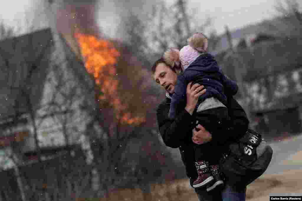 Un bărbat și un copil încearcă să scape din orașul Irpin, pe 6 martie, după un bombardament intens al Rusiei.