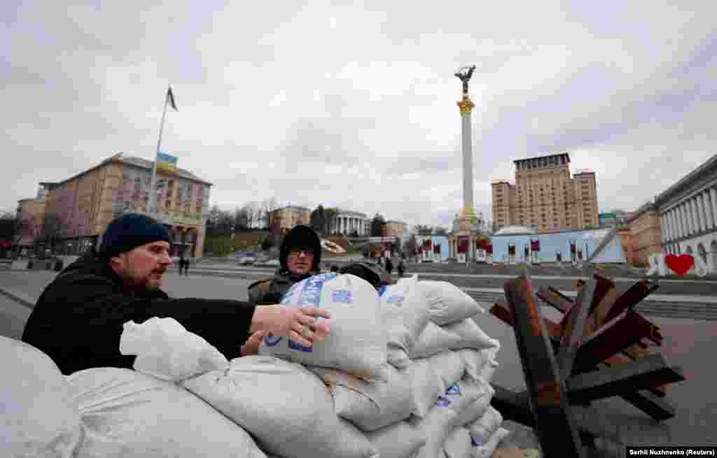 Men emplace sandbags in front of Kyiv&#39;s iconic Independence Monument on March 5.&nbsp;