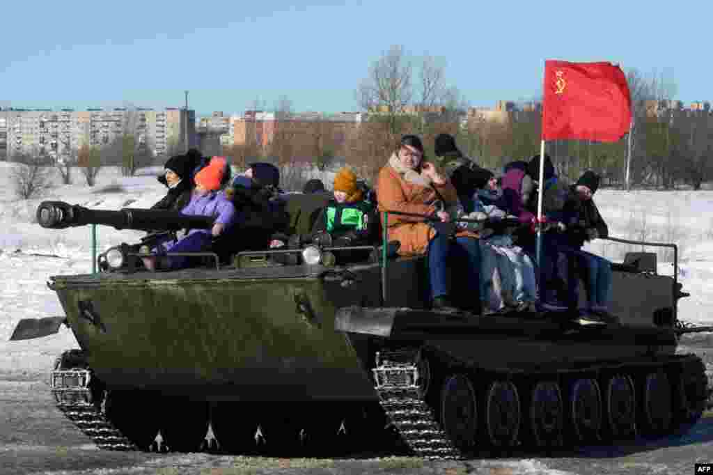 People ride on a military vehicle in an amusement park outside Gatchina in Russia&#39;s Leningrad region on March 6.